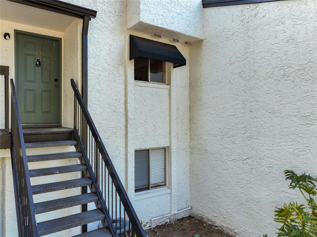 An exterior view of a building entrance with a green door and metal stairs — 4117 S SEMORAN BOULEVARD UNIT 14, ORLANDO, FL