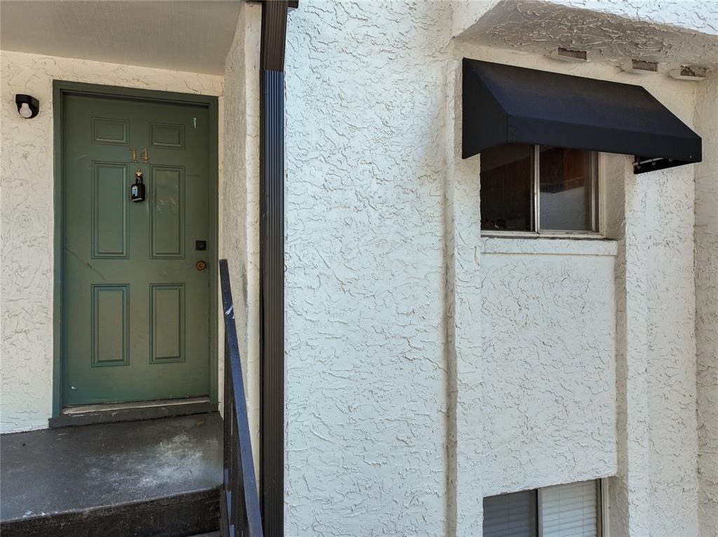 A green front door with a lockbox and a window with a black awning — 4117 S SEMORAN BOULEVARD UNIT 14, ORLANDO, FL
