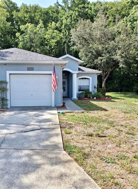 A light blue single-story house features a white garage door and a covered front entrance — 12441 CAVALIER COURT, HUDSON, FL