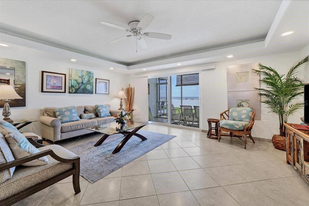 A living room with tile floors, a ceiling fan, and sliding doors overlooking the beach — 6154 MIDNIGHT PASS ROAD UNIT 104, SARASOTA, FL
