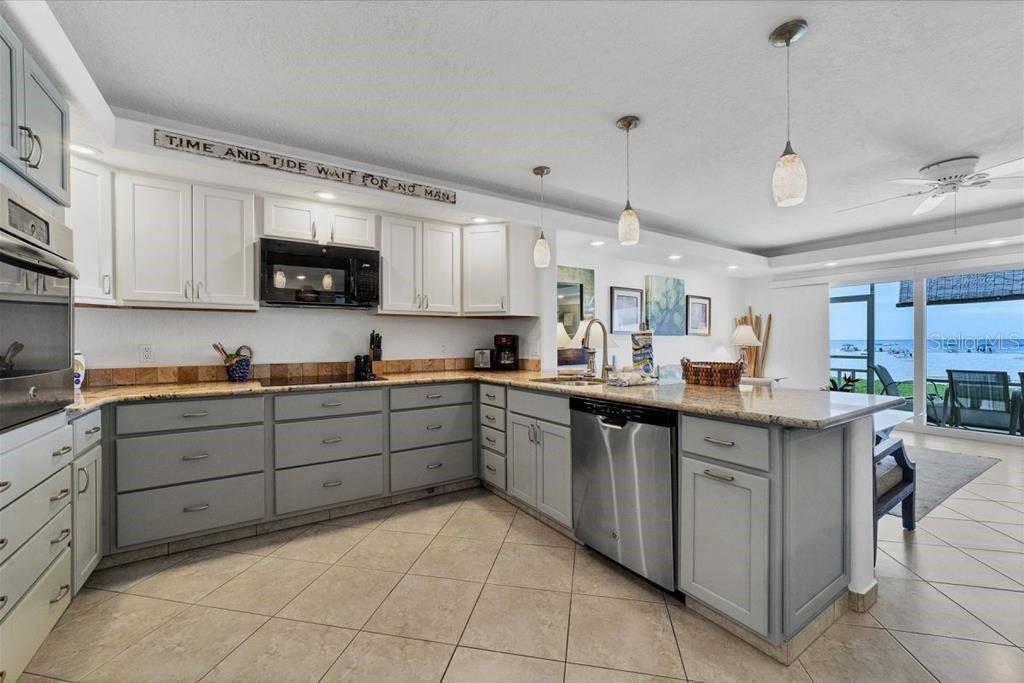 A kitchen with white upper cabinets, grey lower cabinets, granite countertops, and a water view — 6154 MIDNIGHT PASS ROAD UNIT 104, SARASOTA, FL