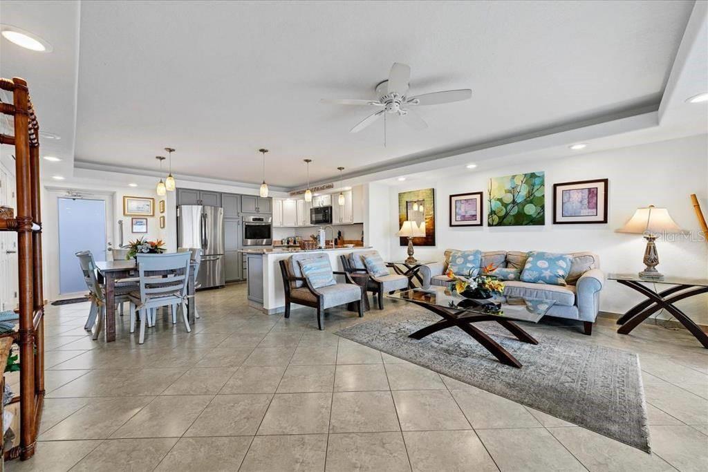 An open-concept living and dining area features tile flooring, a ceiling fan, and kitchen cabinetry — 6154 MIDNIGHT PASS ROAD UNIT 104, SARASOTA, FL