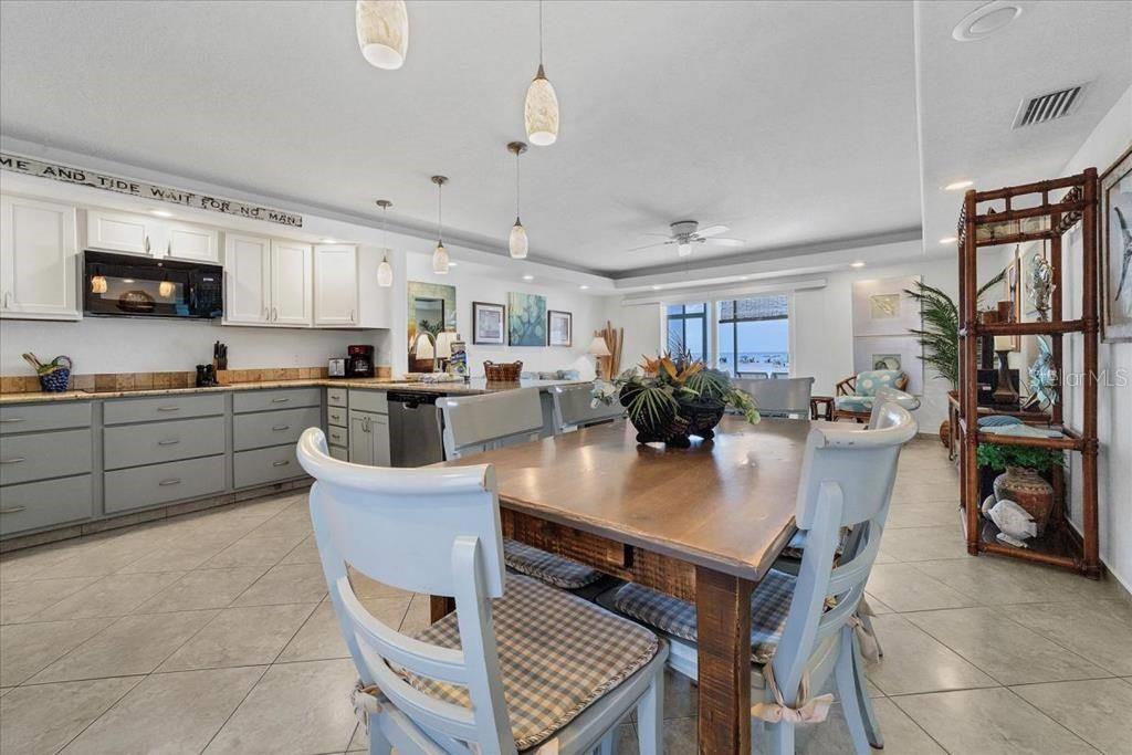 A kitchen and dining area with white cabinets, a wooden table, and ocean views — 6154 MIDNIGHT PASS ROAD UNIT 104, SARASOTA, FL