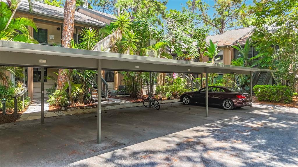 An aerial view shows a residential neighborhood with dense trees, apartment buildings, and paved roads — 1715 PELICAN COVE ROAD UNIT GL339, SARASOTA, FL