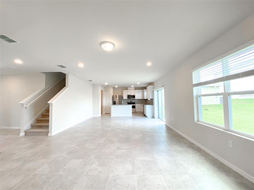 An open-concept living area features tile flooring, a staircase, and a kitchen with white cabinets — 1579 ASPEN AVENUE, DAVENPORT, FL