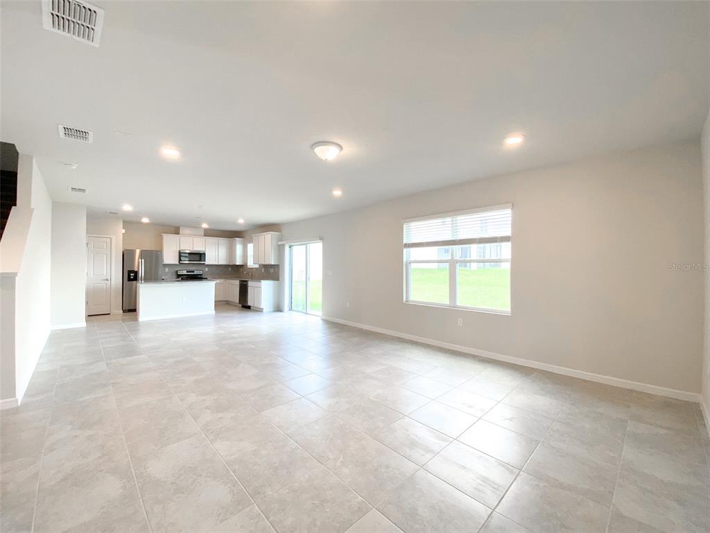 An open-concept living area features light-colored tile flooring, white cabinetry, and a large window — 1579 ASPEN AVENUE, DAVENPORT, FL