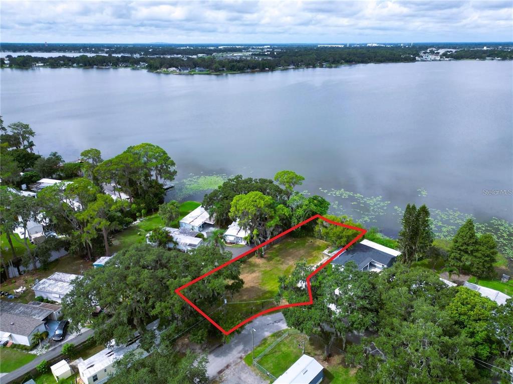 An aerial view shows a vacant, rectangular waterfront lot outlined in red near a lake — 31 SUNSET CIRCLE, LAKE ALFRED, FL