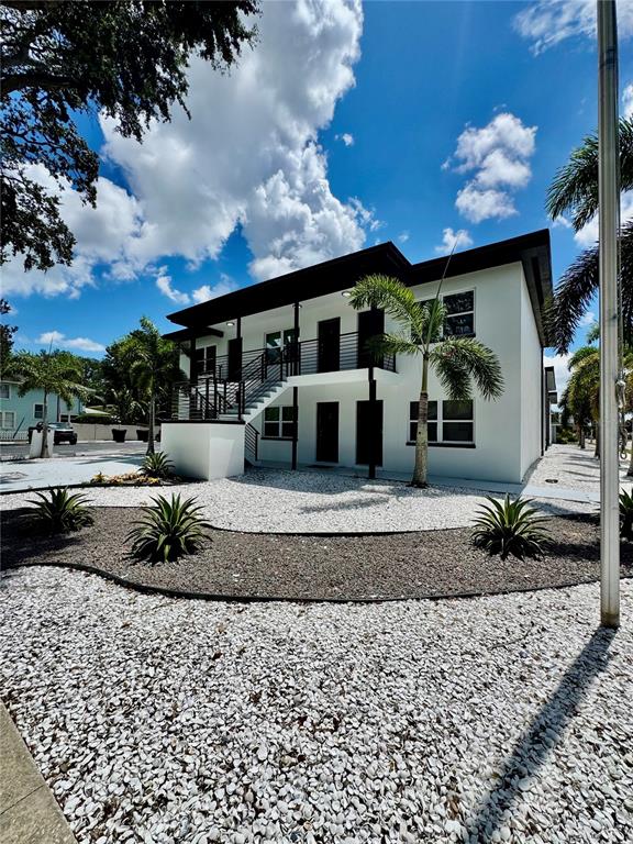 A two-story white apartment building features a black roof, exterior staircases, and palm trees — 1921 DR MARTIN LUTHER KING JR STREET N UNIT A10, ST PETERSBURG, FL