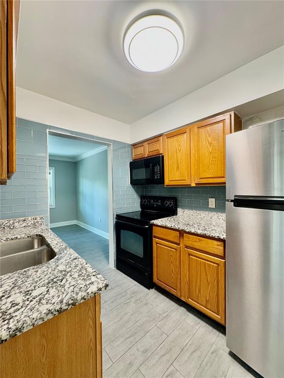 A kitchen features oak cabinets, granite countertops, a stainless steel refrigerator, and light blue tile — 1921 DR MARTIN LUTHER KING JR STREET N UNIT A10, ST PETERSBURG, FL