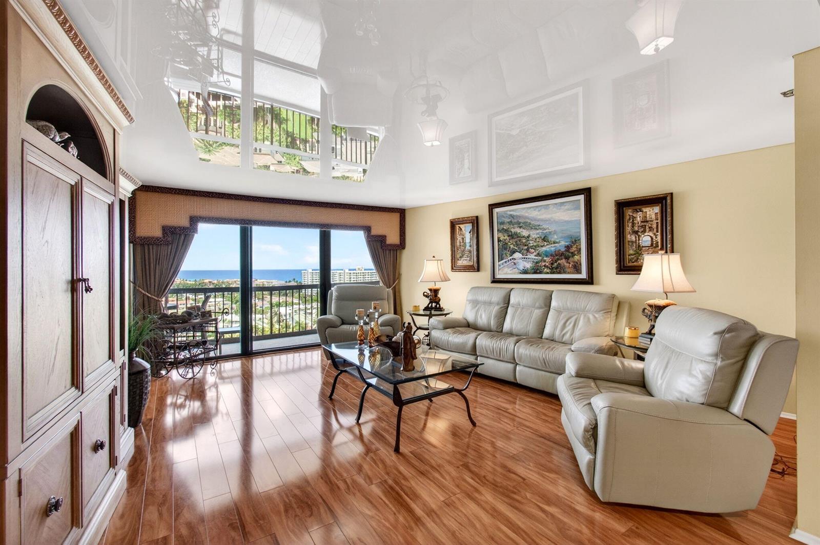 A living room with light wood floors, leather furniture, and a reflective white ceiling — 4740 S Ocean Boulevard # 1503, Boca Raton FL 33487, BOCA RATON, FL
