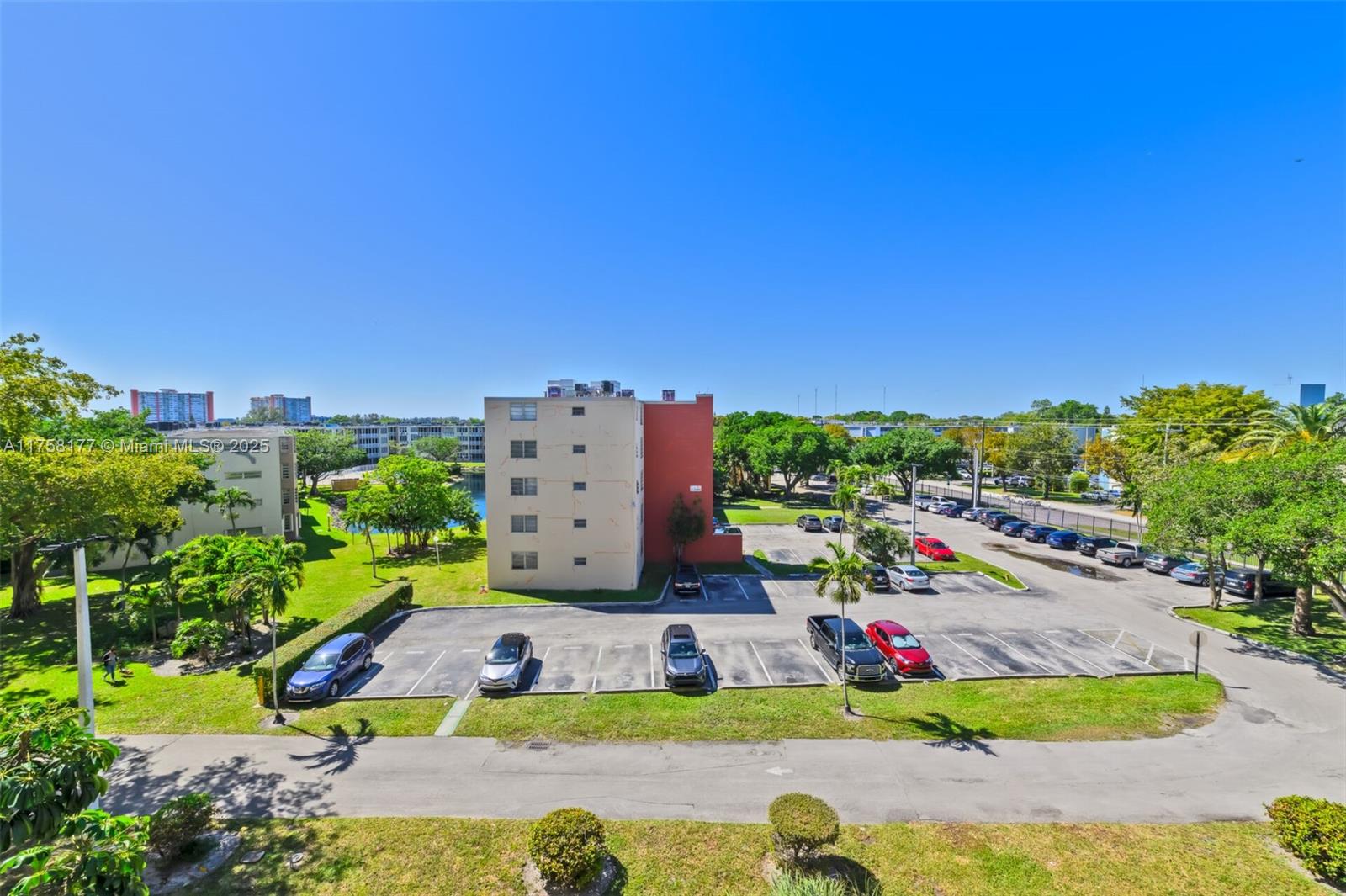 An exterior view shows a multi-story apartment building with a parking lot and surrounding greenery — 1770 NE 191st St # 1, Miami FL 33179, MIAMI, FL