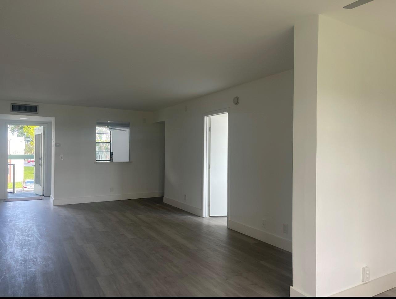 An empty living room features white walls, gray wood-look flooring, and an open doorway — 7460 NW 18th Street # 201, Margate FL 33063, MARGATE, FL