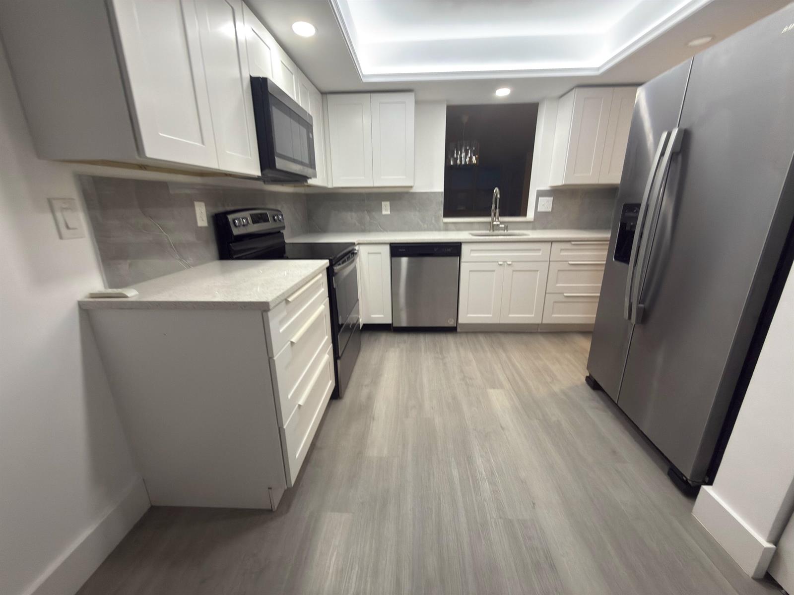 A modern kitchen features white cabinets, stainless steel appliances, grey flooring, and quartz countertops — 7460 NW 18th Street # 201, Margate FL 33063, MARGATE, FL