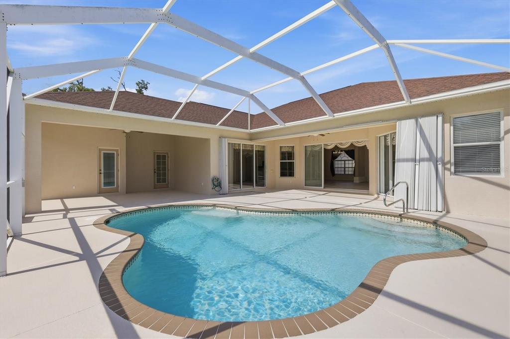 A swimming pool sits on a patio enclosed by a white metal screen cage — 2635 MANASOTA BEACH ROAD, ENGLEWOOD, FL