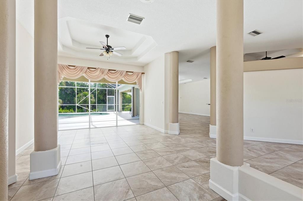 A bright living area features tile floors, decorative columns, and a sliding door to a pool — 2635 MANASOTA BEACH ROAD, ENGLEWOOD, FL