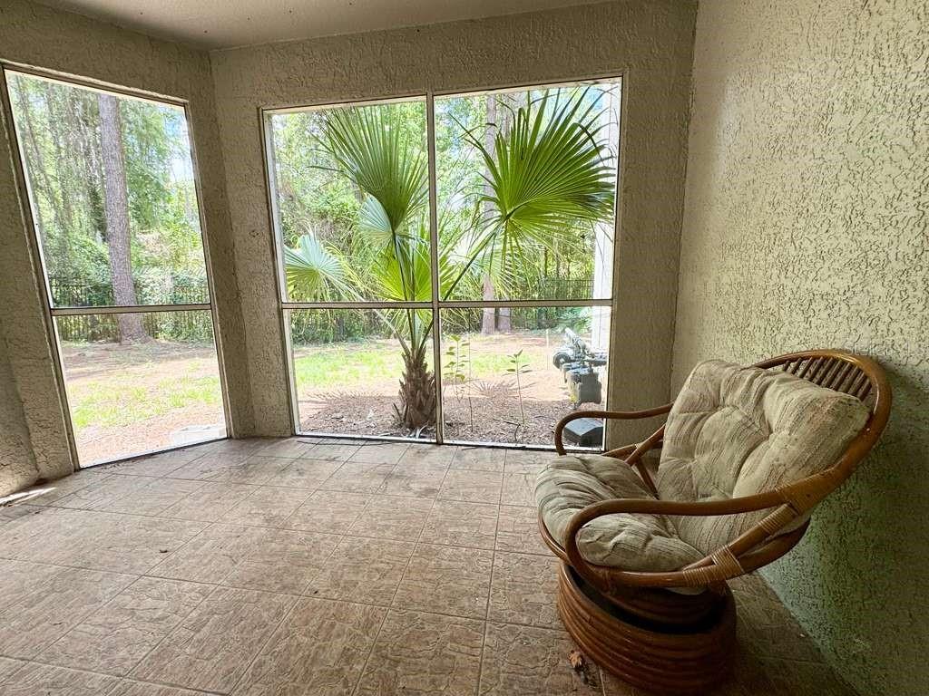 A screened-in porch with tiled flooring, a wicker chair, and a view of palm trees — 3313 S KIRKMAN ROAD UNIT 217, ORLANDO, FL