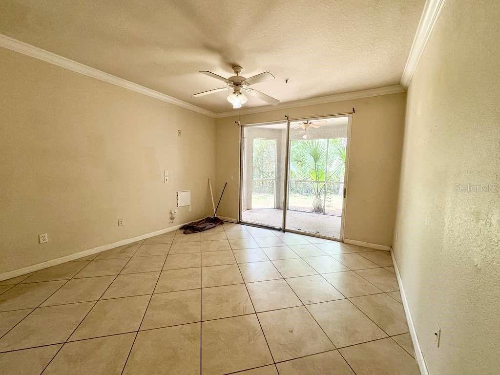 An empty room with beige tile floors, a ceiling fan, and sliding glass doors — 3313 S KIRKMAN ROAD UNIT 217, ORLANDO, FL