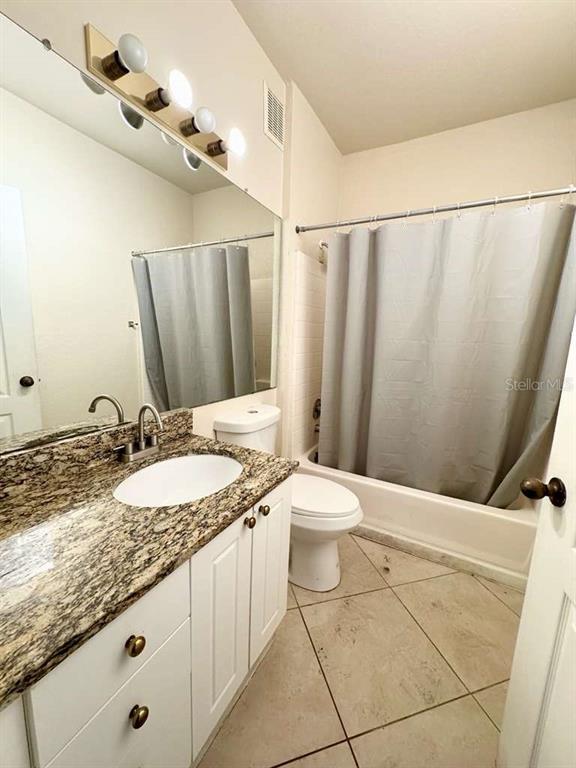 A bathroom features a granite vanity, white cabinets, a mirror, and a shower-tub combination — 3313 S KIRKMAN ROAD UNIT 217, ORLANDO, FL