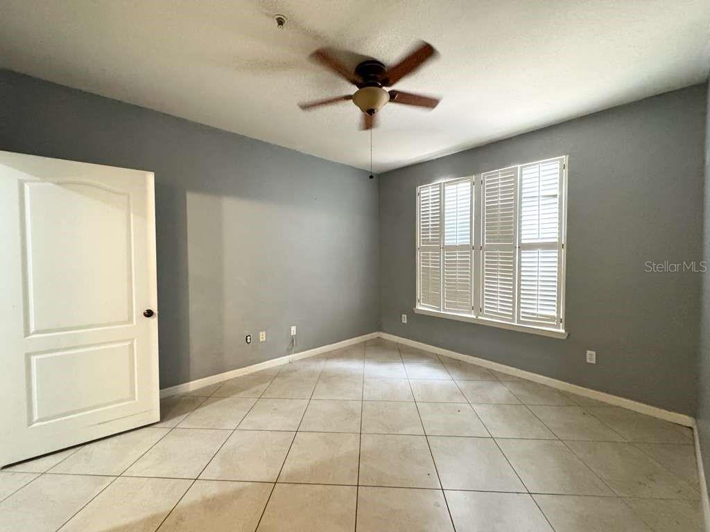 An empty bedroom features gray walls, tile flooring, a ceiling fan, and white plantation shutters — 3313 S KIRKMAN ROAD UNIT 217, ORLANDO, FL
