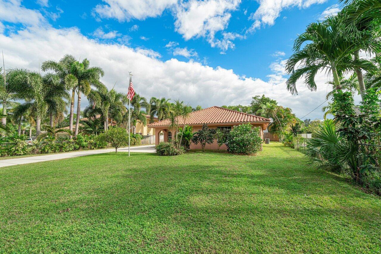 A single-story house with a terracotta tile roof sits on a large grassy lawn — 5592 1st Road, Lake Worth FL 33467, LAKE WORTH, FL