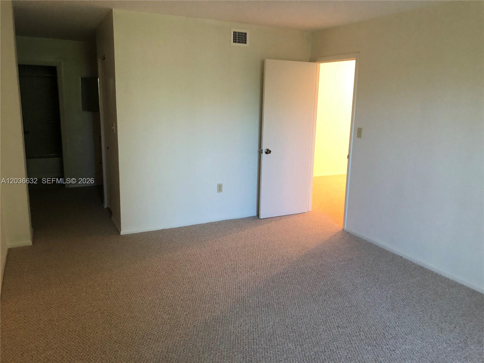 An empty room with beige carpeting, white walls, and an open door leading to another room — 10852 N Kendall Dr # 316, Miami FL 33176, MIAMI, FL
