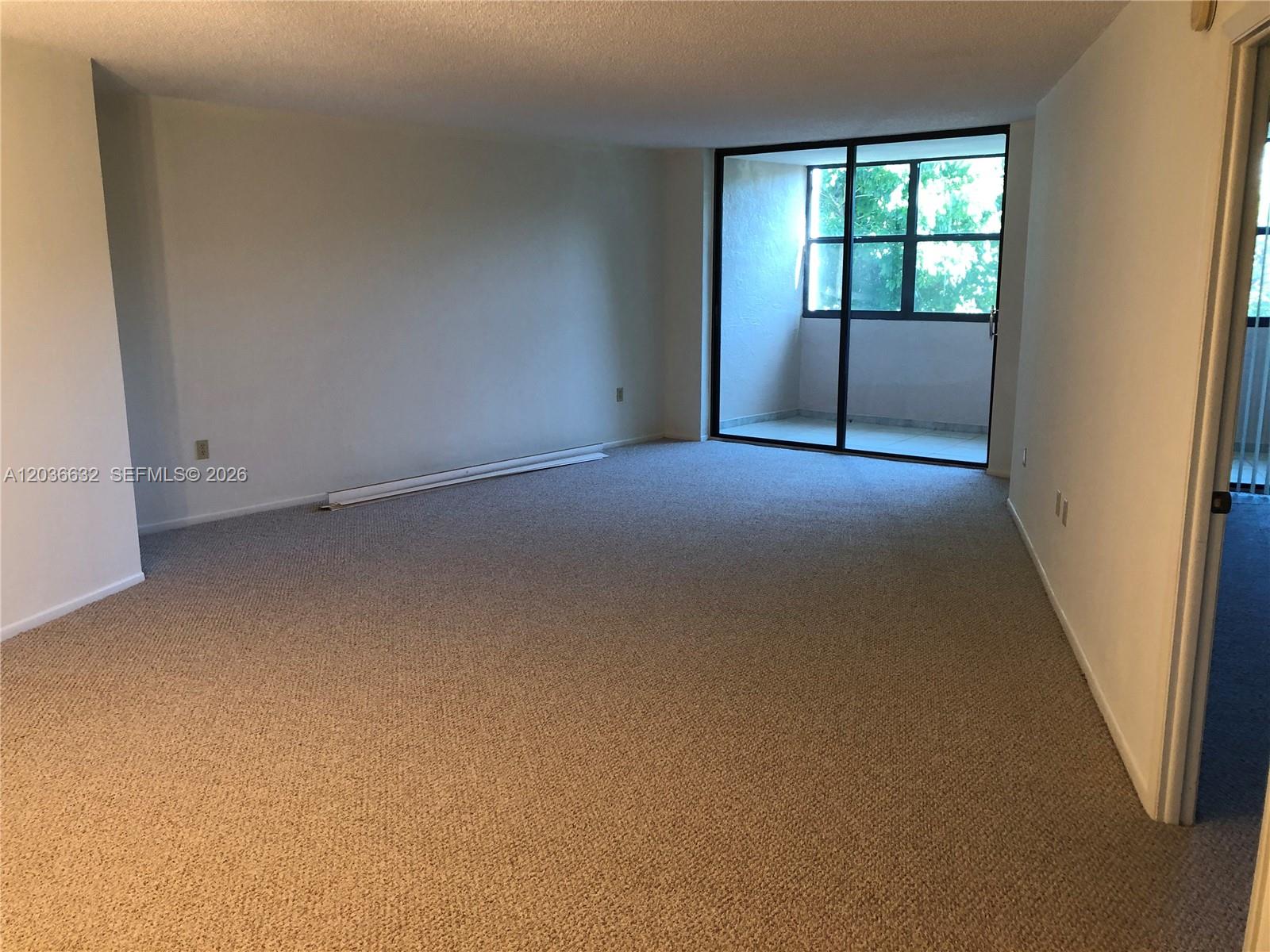 An empty room features beige carpeting, white walls, and a sliding glass door to a balcony — 10852 N Kendall Dr # 316, Miami FL 33176, MIAMI, FL