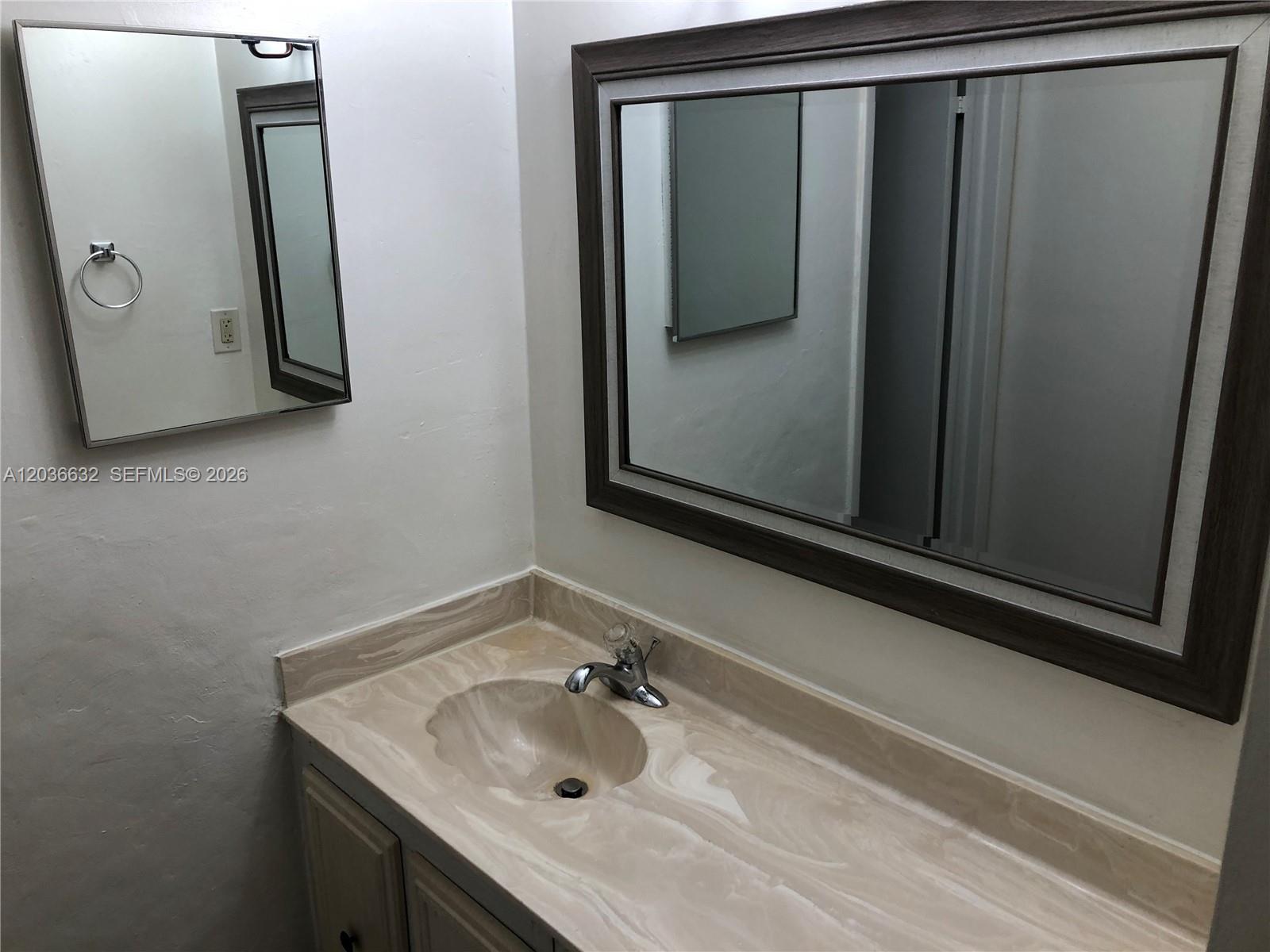A bathroom vanity features a marble-patterned countertop, a chrome faucet, and two wall mirrors — 10852 N Kendall Dr # 316, Miami FL 33176, MIAMI, FL
