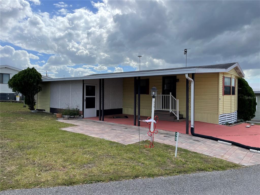 A yellow mobile home features a covered patio, a paved driveway, and a white lattice screen — 251 PATTERSON ROAD UNIT C25, HAINES CITY, FL