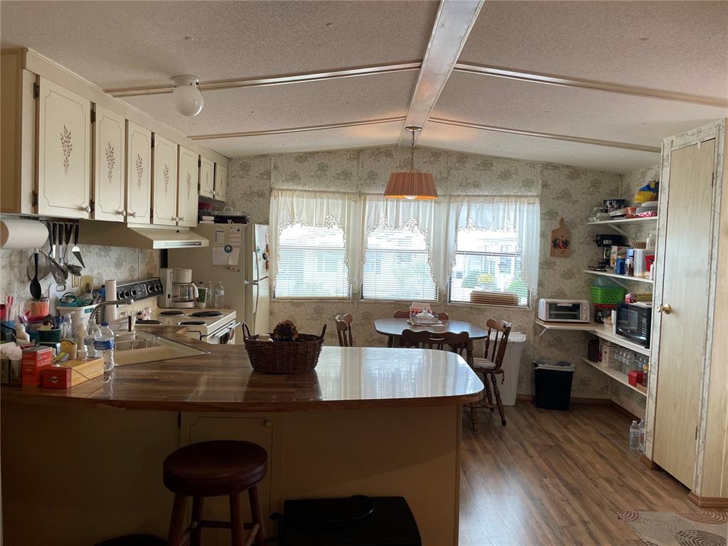 A kitchen with wood-look flooring, white cabinets, a peninsula, and a small dining area — 251 PATTERSON ROAD UNIT C25, HAINES CITY, FL