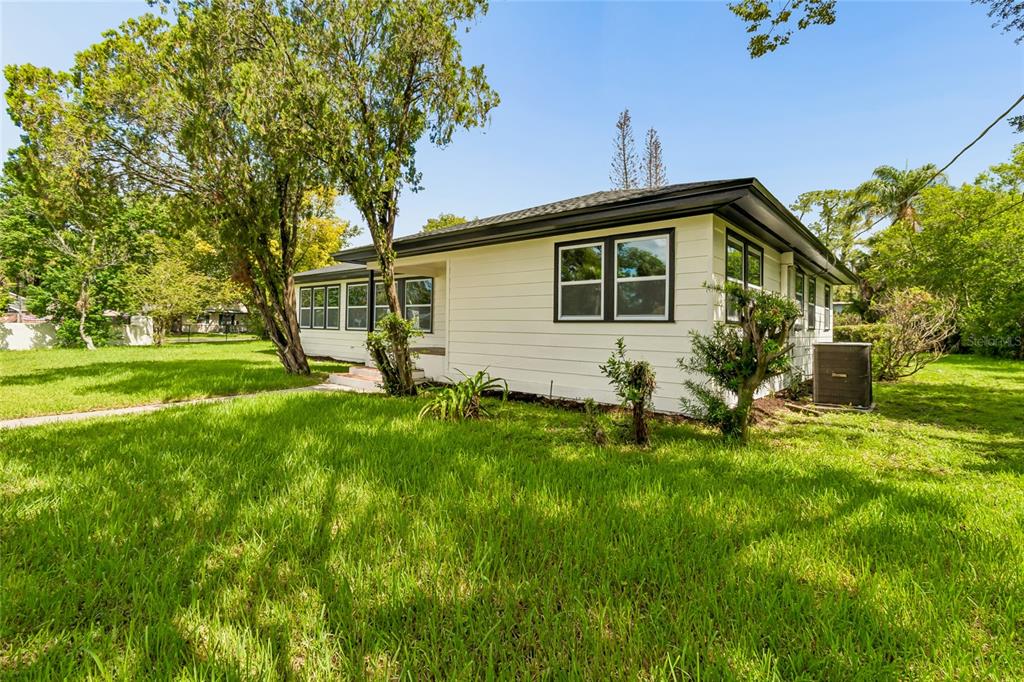 A white, single-story house with a dark roof sits on a grassy lot — 400 PLUMOSA DRIVE, SANFORD, FL