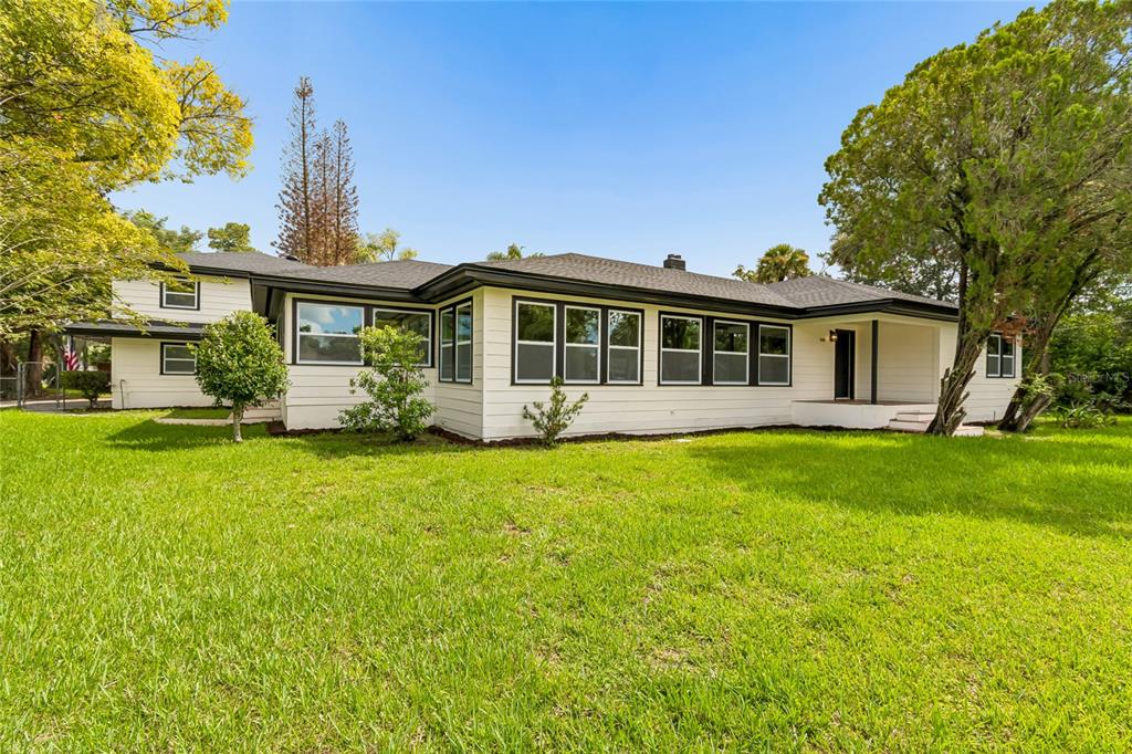 A single-story house with white siding, dark trim, and a dark roof sits on grass — 400 PLUMOSA DRIVE, SANFORD, FL