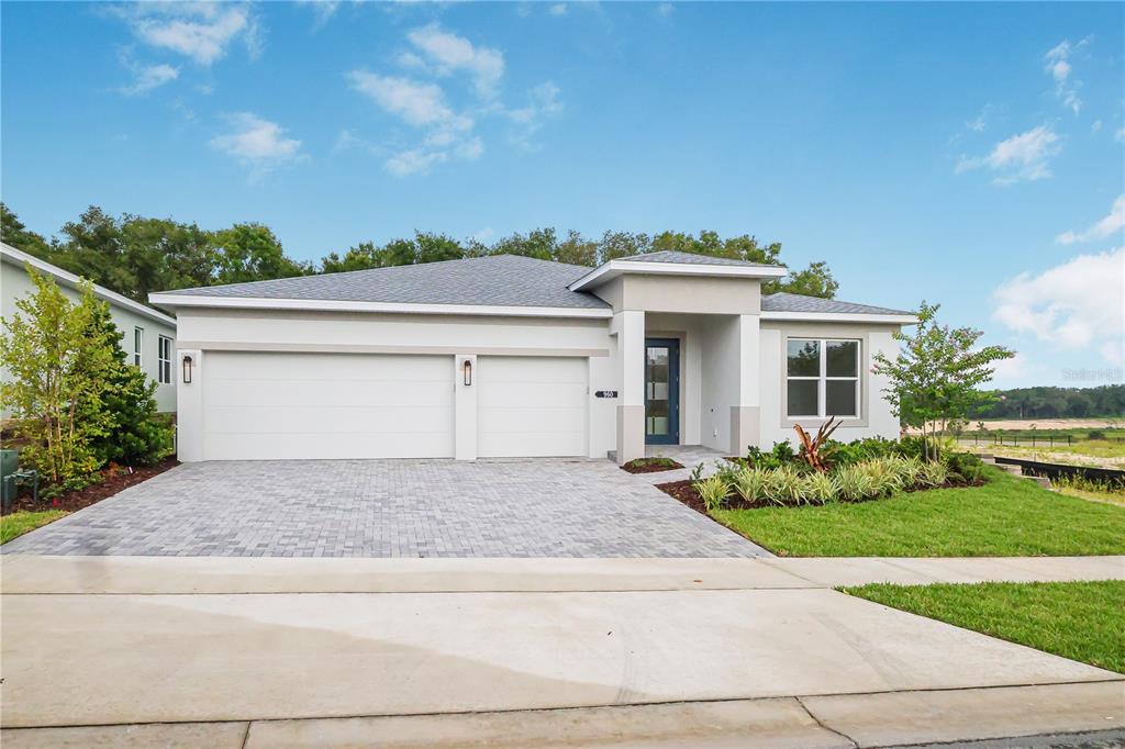A single-story house with a two-car garage, paved driveway, and a blue front door — 960 CLUB CRESSWIND DRIVE, LADY LAKE, FL