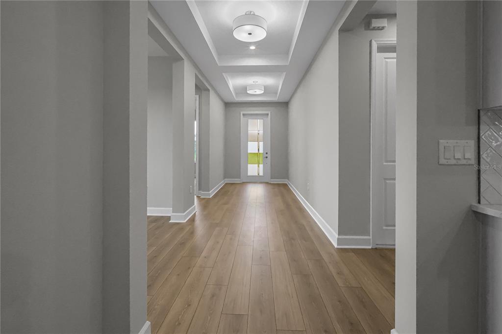 A hallway with light wood flooring, gray walls, and a tray ceiling with recessed lighting — 960 CLUB CRESSWIND DRIVE, LADY LAKE, FL