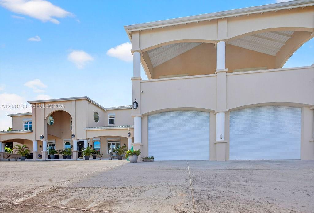 The exterior of a large beige house features a multi-car garage and arched architectural details — 15 Paradise View Villa, 00000, FL