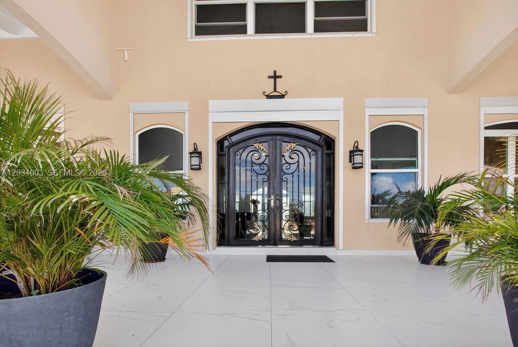 A front entrance features double iron doors with gold accents and two potted palm trees — 15 Paradise View Villa, 00000, FL