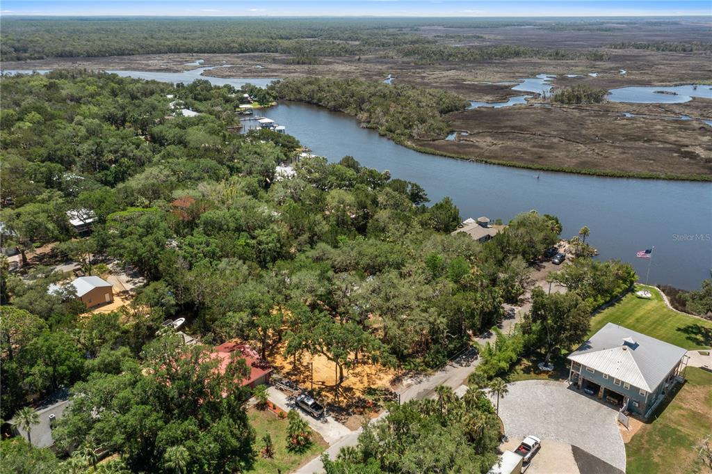 An aerial view shows a wooded residential lot situated along a river and marshland — 6845 S MASON CREEK ROAD, HOMOSASSA, FL