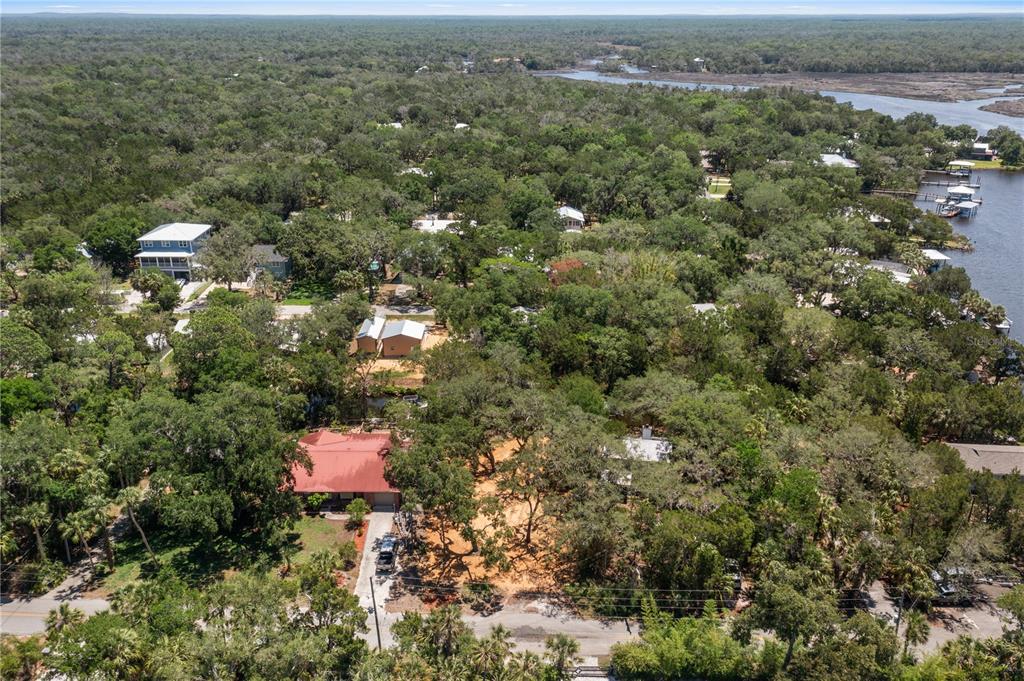 An aerial view shows a red-roofed house surrounded by dense trees near a coastal waterway — 6845 S MASON CREEK ROAD, HOMOSASSA, FL