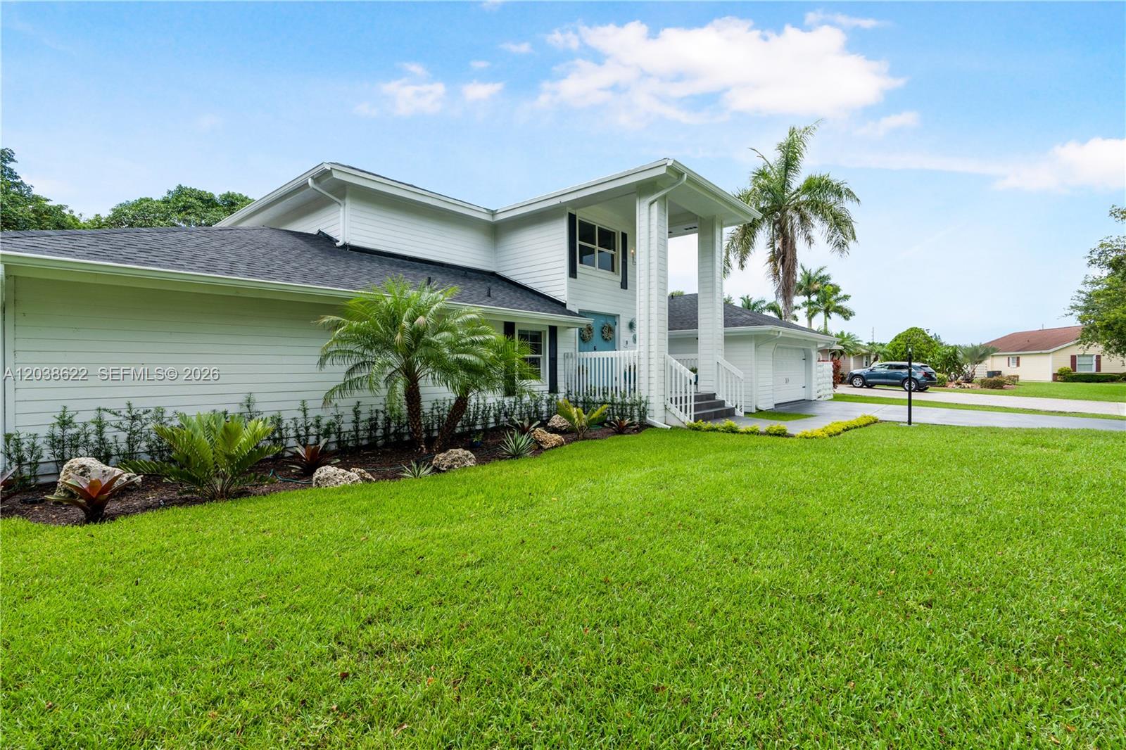 A two-story white house with a front porch and landscaped lawn under a blue sky — 14830 SW 149th St, Miami FL 33196, MIAMI, FL