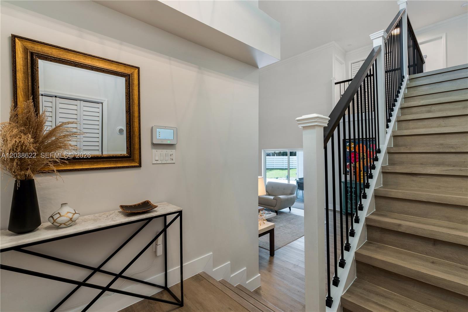 A foyer features a marble console table, a gold-framed mirror, and a wooden staircase — 14830 SW 149th St, Miami FL 33196, MIAMI, FL