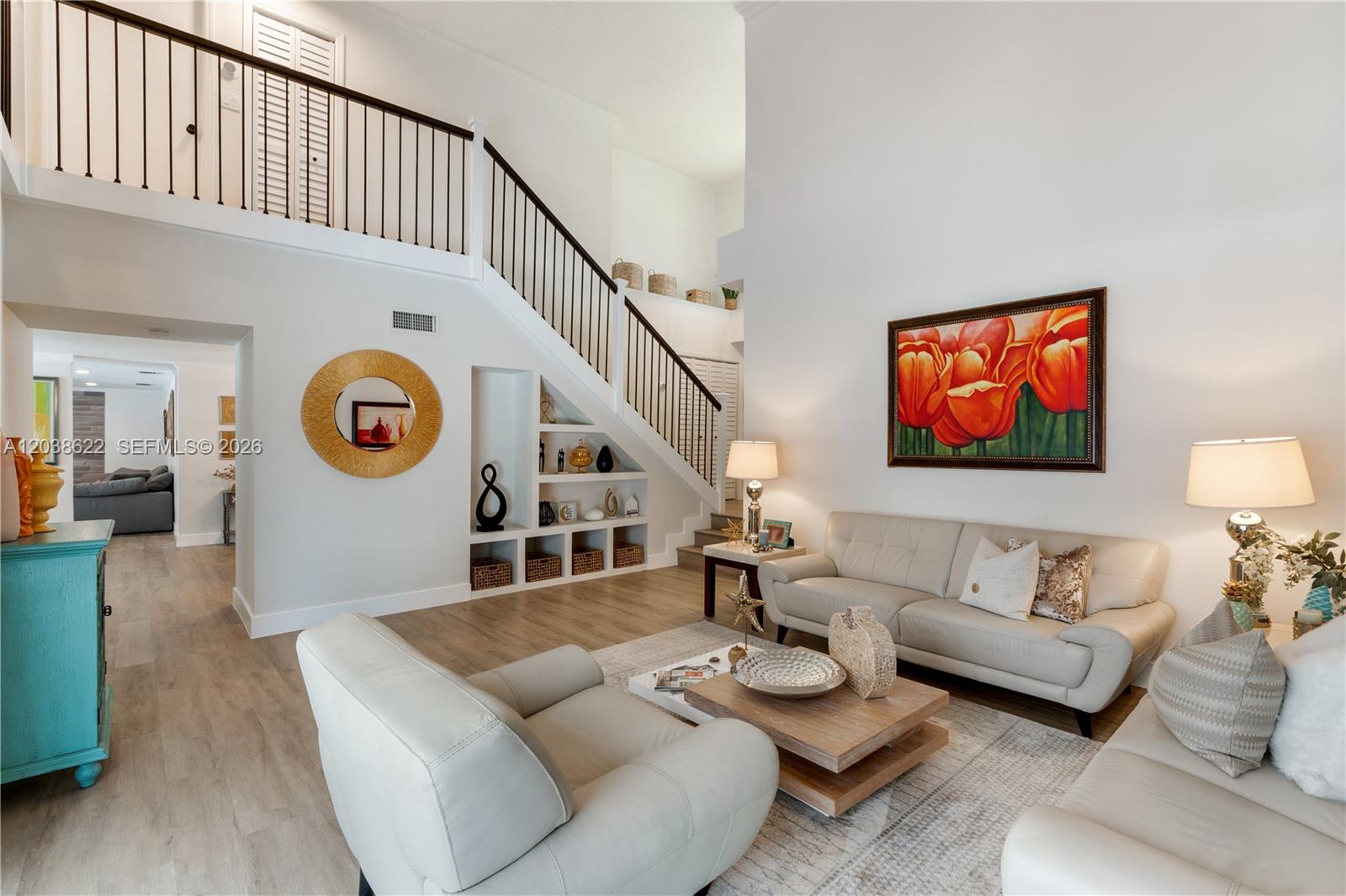 A living room features a staircase, built-in shelving, light wood floors, and neutral furniture — 14830 SW 149th St, Miami FL 33196, MIAMI, FL