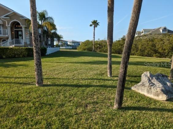 A grassy vacant lot with palm trees and neighboring houses in the background — 4743 JENNMAR WAY, NEW PORT RICHEY, FL