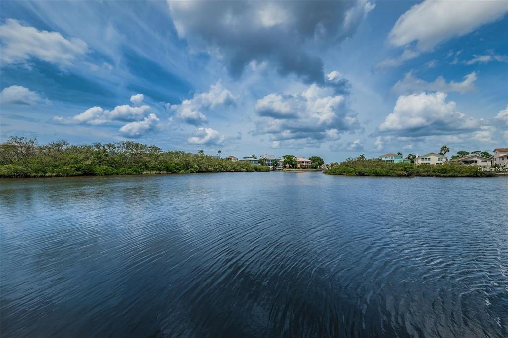A view of a calm waterway surrounded by mangroves with houses in the distance — 4743 JENNMAR WAY, NEW PORT RICHEY, FL
