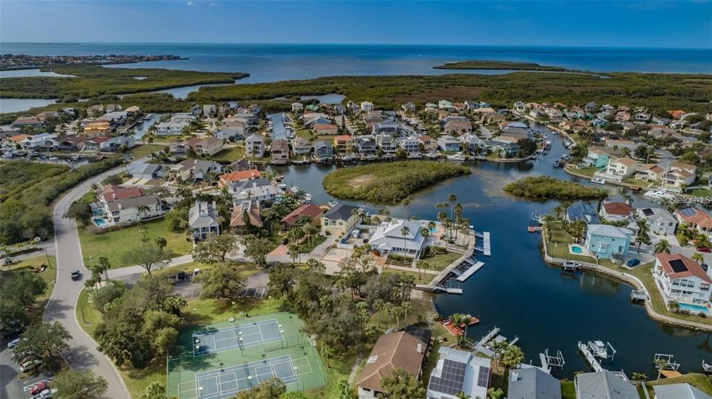 An aerial view of a waterfront residential neighborhood featuring houses, canals, and tennis courts — 4743 JENNMAR WAY, NEW PORT RICHEY, FL