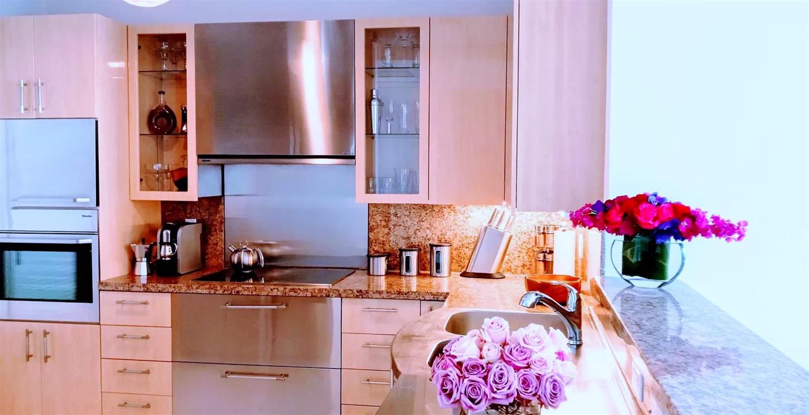 A modern kitchen features light wood cabinets, stainless steel appliances, and granite countertops — 100 S Pointe Drive # 602, Miami Beach FL 33139, MIAMI BEACH, FL