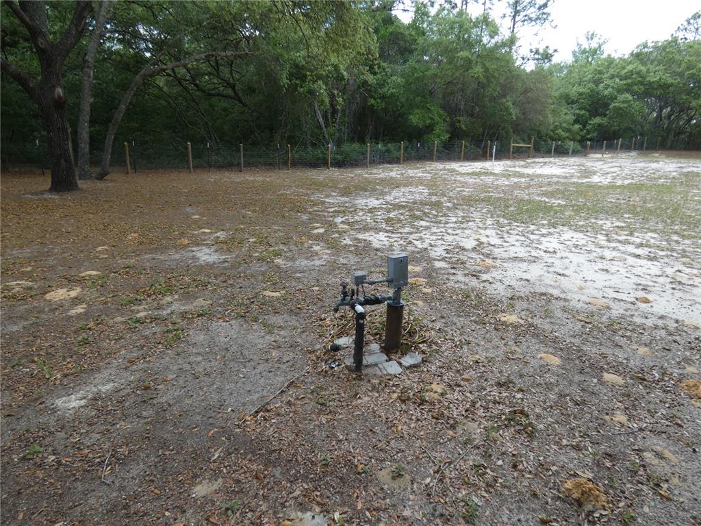 A water well pump sits in a sandy, partially wooded lot with a wire fence — 20865 SW 70TH STREET, DUNNELLON, FL