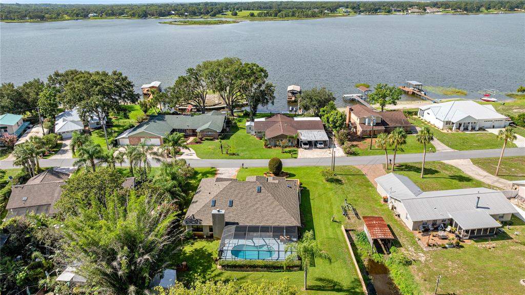An aerial view shows several houses with pools and docks along a large lake — 36 SE CHINICA DRIVE, SUMMERFIELD, FL