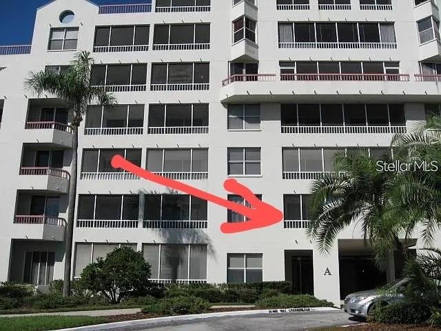 An exterior view of a multi-story white apartment building with a red arrow pointing toward a balcony — 2333 FEATHER SOUND DRIVE UNIT A208, CLEARWATER, FL