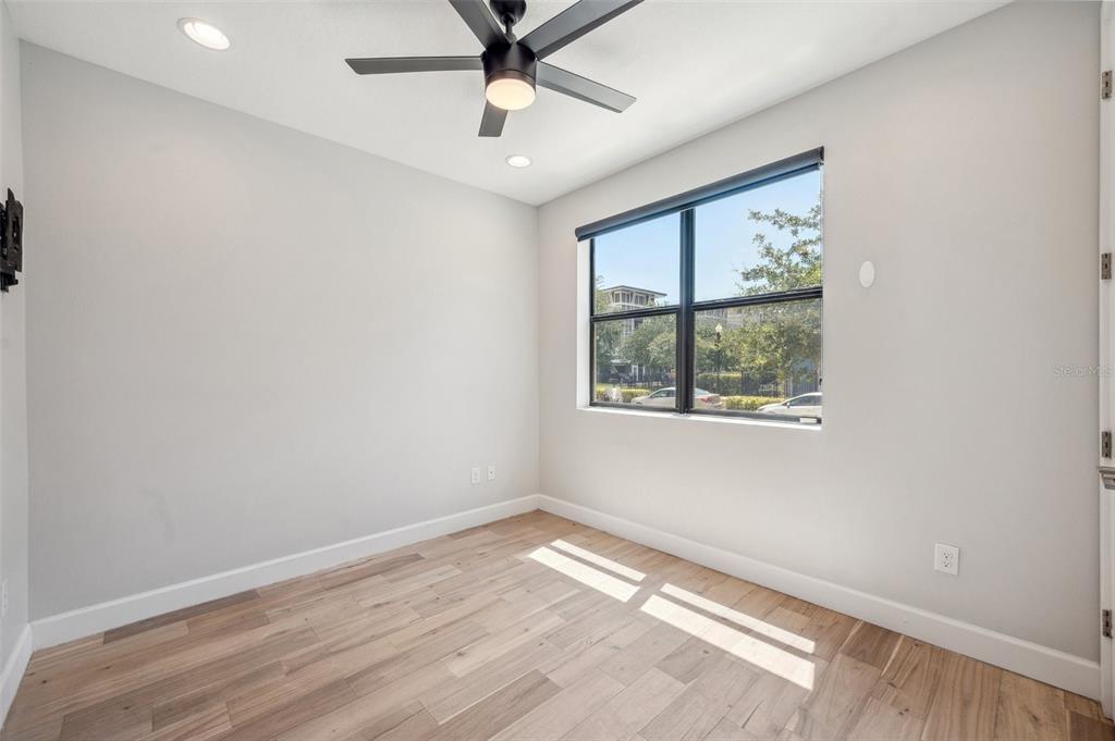 An empty room features light gray walls, wood-look flooring, a ceiling fan, and a window — 401 N OREGON AVENUE UNIT 9, TAMPA, FL