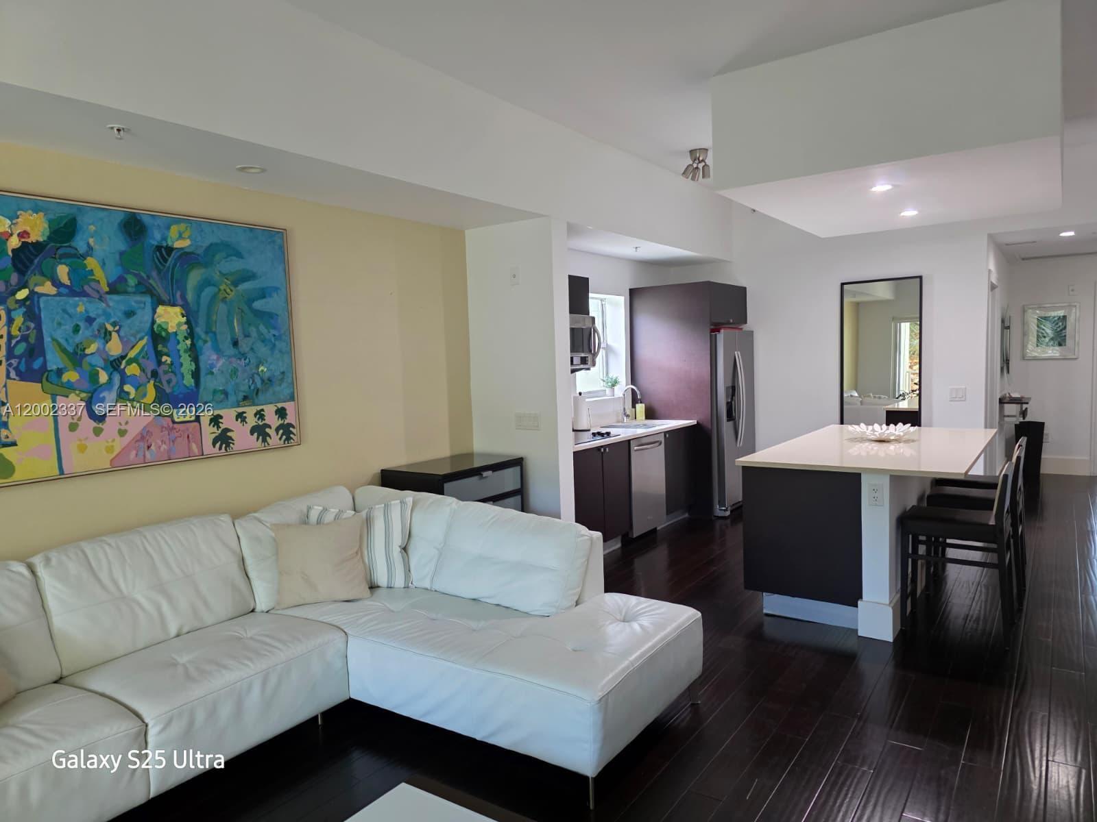 A living room with a white sectional sofa and a kitchen featuring dark cabinetry — 5300 NW 87th Ave # 1416, Doral FL 33178, DORAL, FL