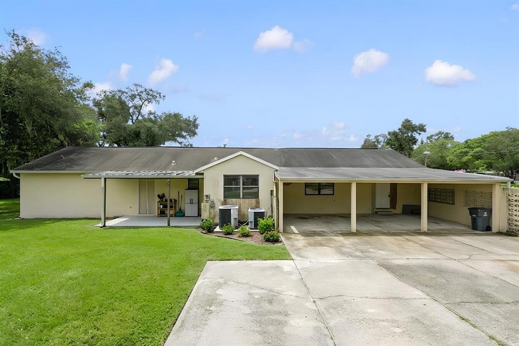 The exterior of a single-story house features a concrete driveway, a carport, and a patio — 11735 MARJORY AVENUE, TAMPA, FL